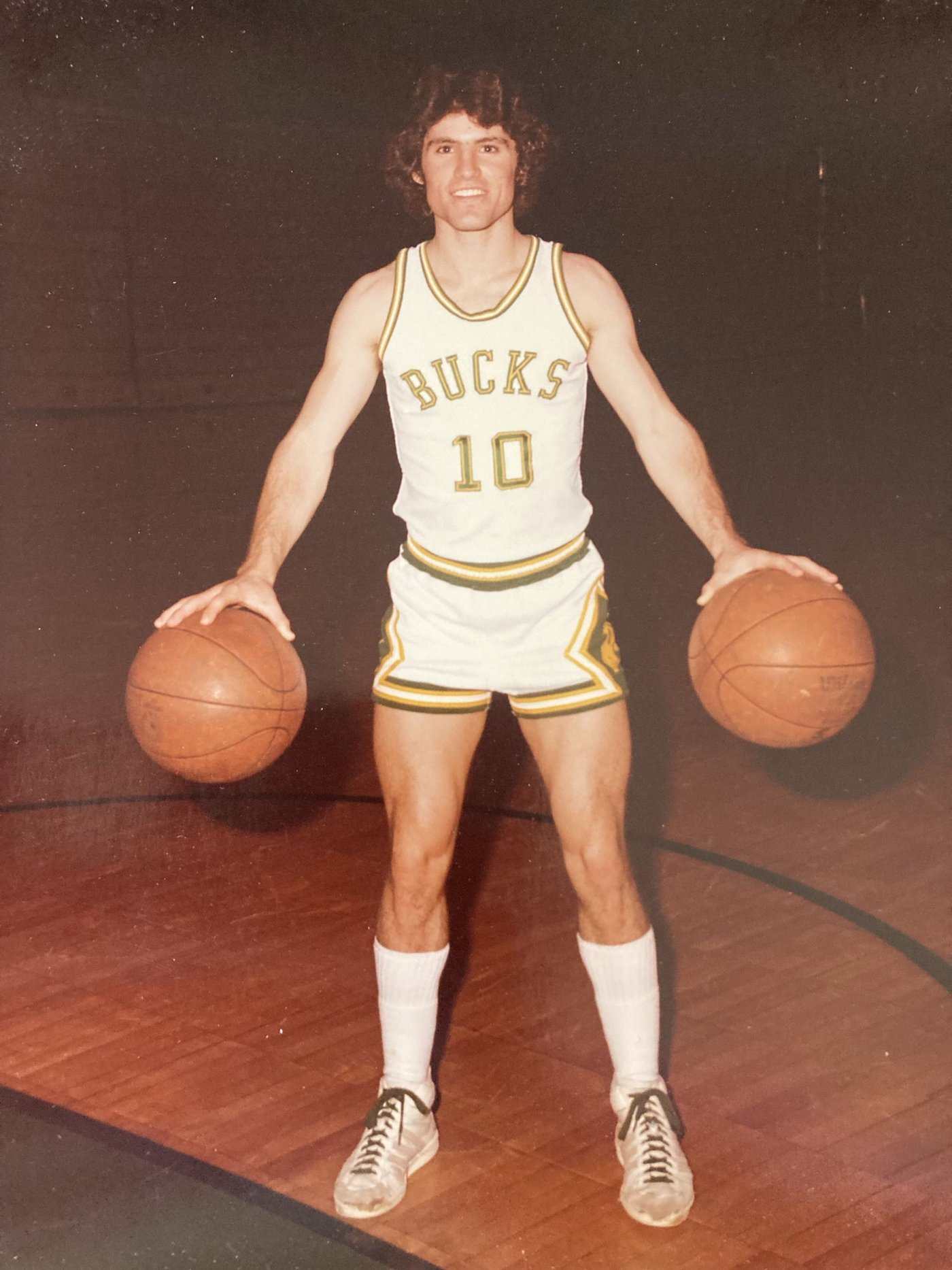 Richard Heriza in his Bucks #10 jersey holding two basketballs